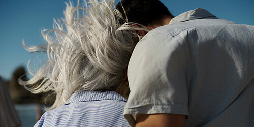 A younger woman fluffing the pillows of an older woman in bed A younger woman fluffing the pillows of an older woman in bed